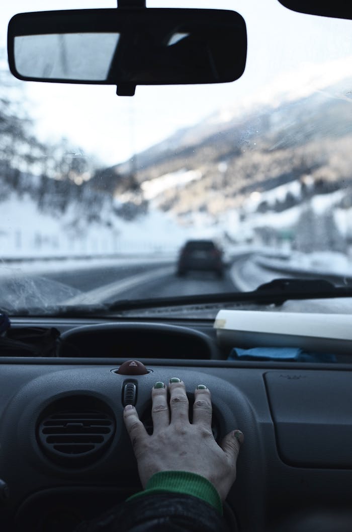 Driving through snowy mountains in winter. Hand on car air vent. Road trip experience.